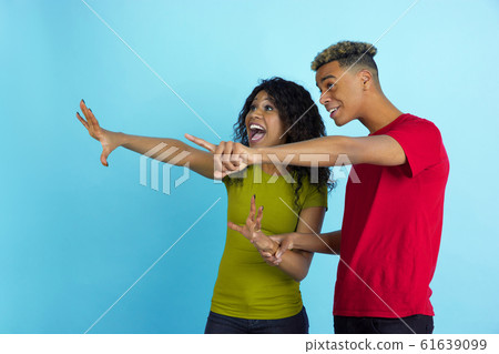 Young emotional african-american man and woman on blue background 61639099