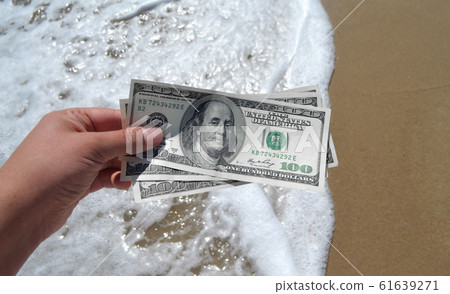 Girl holding a money bill of 300 dollars on background of sea waves 61639271