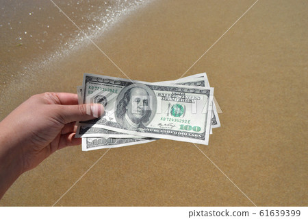 Girl holding money bill of 300 dollars on background of sea ocean 61639399