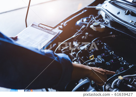 Car mechanic holding clipboard and checking to 61639427