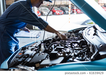 Car mechanic holding clipboard and checking to 61639429