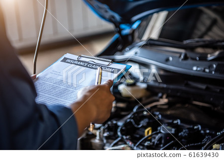 Car mechanic holding clipboard and checking to 61639430
