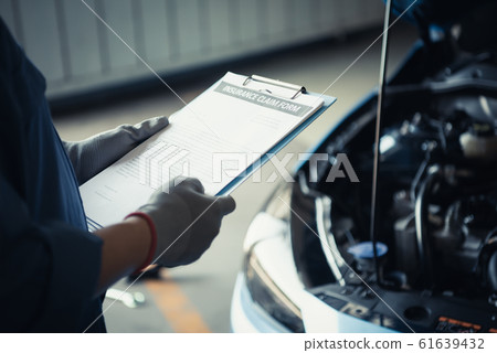 Car mechanic holding clipboard and checking to 61639432