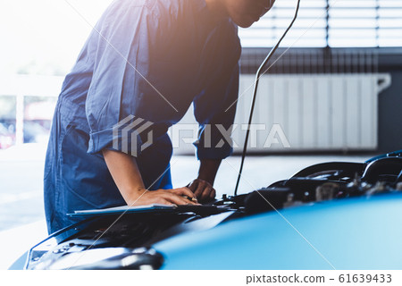Car mechanic holding clipboard and checking to 61639433