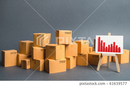 A big pile of cardboard boxes and a stand with information chart. Increasing consumer demand, exports or imports. rate growth of production of goods and products, increasing economic indicators. A big pile of cardboard boxes and a stand with information chart. Increasing consumer demand, exports or imports. rate growth of production of goods and products, increasing economic indicators. 61639577