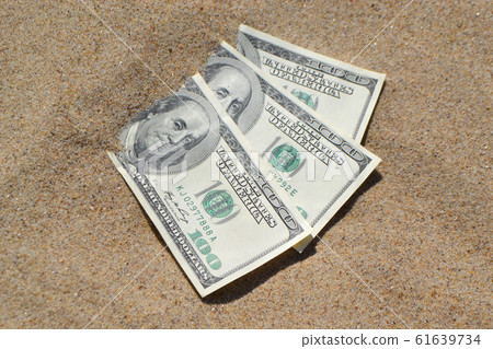 Money dolars half covered with sand lie on beach close-up. Money dolars half covered with sand lie on beach close-up. 61639734