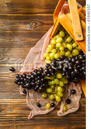 Picture of grapes green and black in wooden basket on table Picture of grapes green and black in wooden basket on table 61640107
