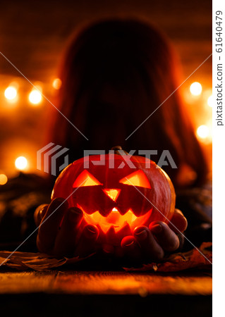 Photo of witch with long hair holding pumpkin 61640479