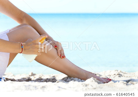 Woman applying sun protection cream at beach 61640545