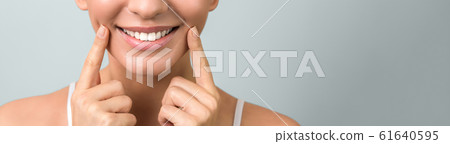 close up a beautiful healthy smile of a young woman on light blue background with copyspace close up a beautiful healthy smile of a young woman on light blue background with copyspace 61640595