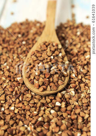 Buckwheat groats in a wooden spoon on a white wooden background. The concept of healthy nutrition and diet. Zero wast. Close-up. Buckwheat groats in a wooden spoon on a white wooden background. The concept of healthy nutrition and diet. Zero wast. Close-up. 61641039