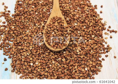 Buckwheat groats in a wooden spoon on a white wooden background. The concept of healthy nutrition and diet. Zero wast. Close-up. Buckwheat groats in a wooden spoon on a white wooden background. The concept of healthy nutrition and diet. Zero wast. Close-up. 61641042