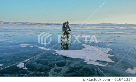 Man is riding bicycle on the ice. Ice of frozen Lake Baikal. Rid 61641334