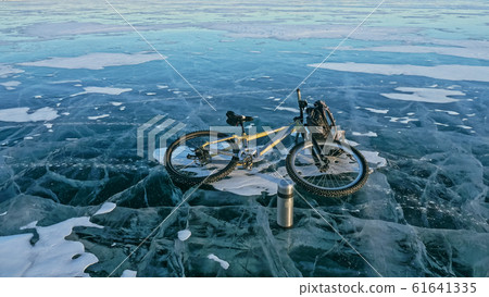 Man and his bicycle on ice. He looks at the beautiful ice in the Man and his bicycle on ice. He looks at the beautiful ice in the 61641335