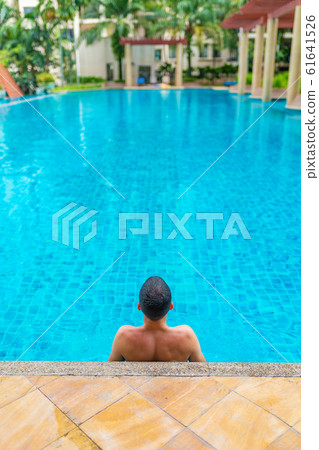 The guy is relaxing by the pool on a hot summer The guy is relaxing by the pool on a hot summer 61641526