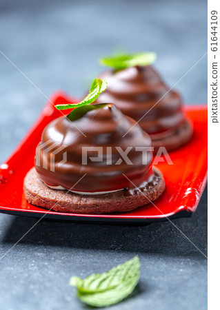 Chocolate mini cakes with green mint leaves. Chocolate mini cakes with green mint leaves. 61644109