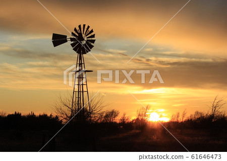 Kansas Country Windmill silhouette with a colorful sky,Sun and tree's out in the country. 61646473