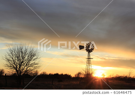 Kansas Country Windmill silhouette with a colorful sky,Sun and tree's out in the country. 61646475