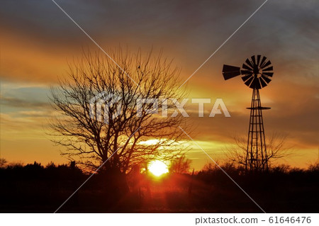 Kansas Country Windmill silhouette with a colorful sky,Sun and tree's out in the country. 61646476