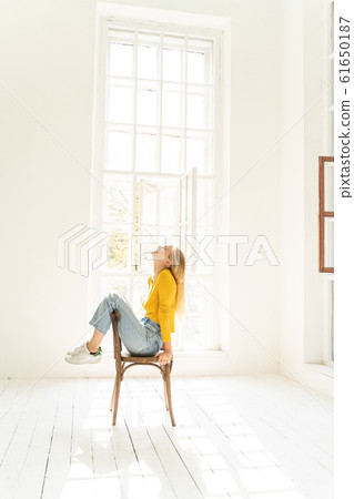 Relaxed lady in yellow sweater posing for camera in the room Relaxed lady in yellow sweater posing for camera in the room 61650187