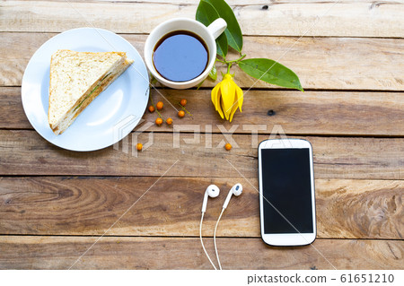 mobile phone with breakfast hot coffee espresso ,sanwich and yellow flower ylang ylang 61651210