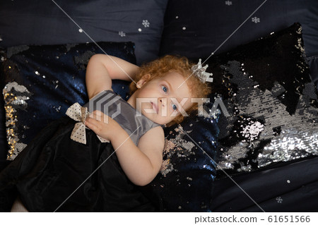 Beautiful little girl child on a New Year's bed. 61651566