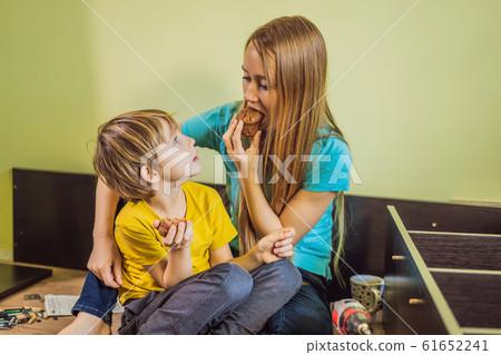 Mother and son assembling furniture. They take a break and eat cupcakes. Boy helping his mom at home 61652241