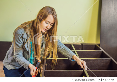 Caucasian woman using screwdriver for assembling furniture Caucasian woman using screwdriver for assembling furniture 61652276