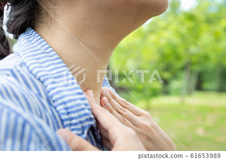 Sick woman suffering from sore throat,painful swallowing,tonsillitis,irritation,asian female patient checking thyroid gland by herself,holding hand on her neck in outdoor park,inflammation,laryngitis, Sick woman suffering from sore throat,painful swallowing,tonsillitis,irritation,asian female patient checking thyroid gland by herself,holding hand on her neck in outdoor park,inflammation,laryngitis, 61653989