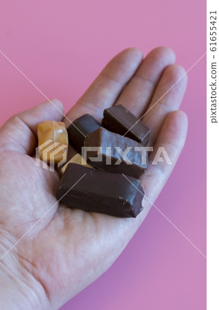 Hand with chocolates on a pink background. Hand with chocolates on a pink background. 61655421