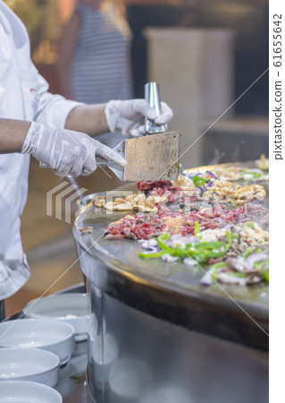 A cook in a restaurant fries food on a large iron 61655642