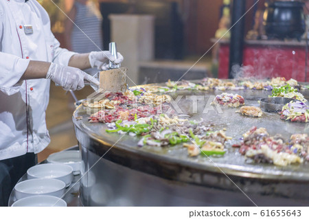 The cook in the restaurant fries food on a large The cook in the restaurant fries food on a large 61655643