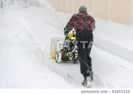 man operating snow blower to remove snow on 61655710