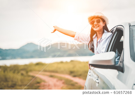 Happy woman waving hand outside open window car 61657268
