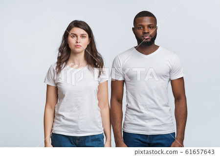 Interracial couple posing with serious face expressions over light background 61657643