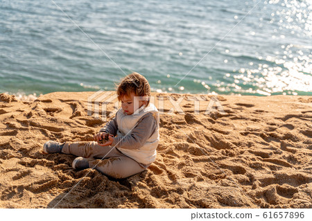 Young child on the sand beach in winter in Spain. Traveling to the nature. Toddler play outdoors 61657896