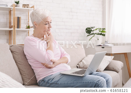Puzzled senior lady looking at laptop with perplexity Puzzled senior lady looking at laptop with perplexity 61658121