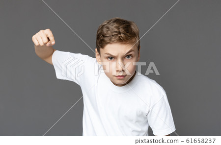 Furious teenager punching fist with anger at camera Furious teenager punching fist with anger at camera 61658237
