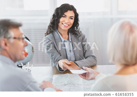Woman giving tickets to happy mature couple Woman giving tickets to happy mature couple 61658355