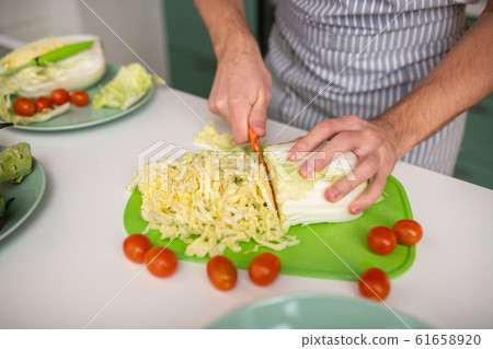 Cook cutting cabbage for a vegetable salad Cook cutting cabbage for a vegetable salad 61658920