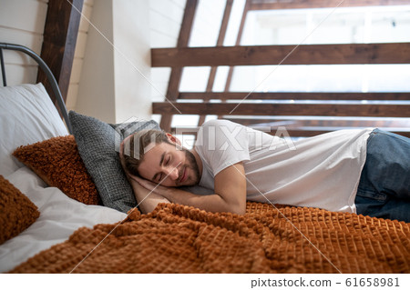 Sleepy young man lying in his bedroom Sleepy young man lying in his bedroom 61658981