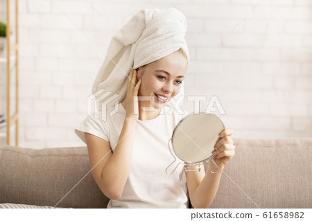 Girl looking at mirror, wearing towel on head after shower Girl looking at mirror, wearing towel on head after shower 61658982