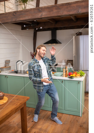 Man wearing wireless earphones listening to music while cooking Man wearing wireless earphones listening to music while cooking 61659161