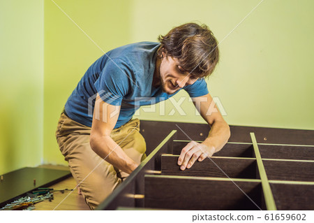 Frustrated Man Putting Together Self Assembly Furniture Frustrated Man Putting Together Self Assembly Furniture 61659602