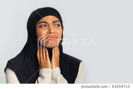 Muslim woman suffering from sore throat, touching her neck with hands Muslim woman suffering from sore throat, touching her neck with hands 61659713