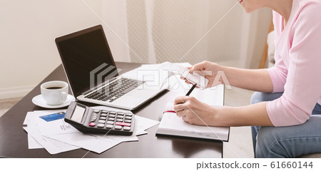 Senior lady writing calculation in notebook with bills Senior lady writing calculation in notebook with bills 61660144