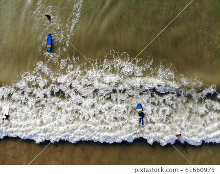 Aerial view of surfers waiting the waves in the dark, brown water in Bali, Indonesia 61660975