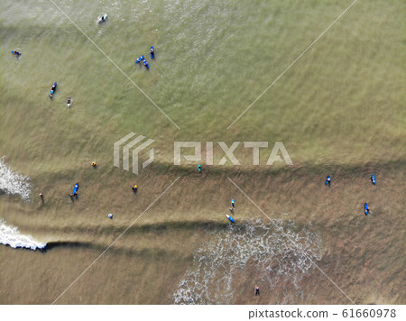 Aerial view of surfers waiting the waves in the dark, brown water in Bali, Indonesia 61660978