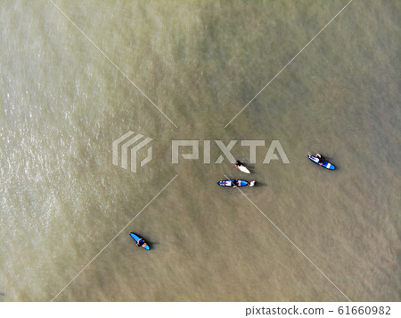 Aerial view of surfers waiting the waves in the dark, brown water in Bali, Indonesia 61660982