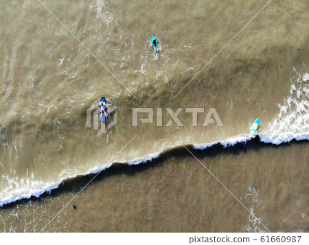 Aerial view of surfers waiting the waves in the dark, brown water in Bali, Indonesia 61660987